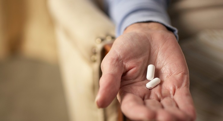 man's hand holding pill capsules