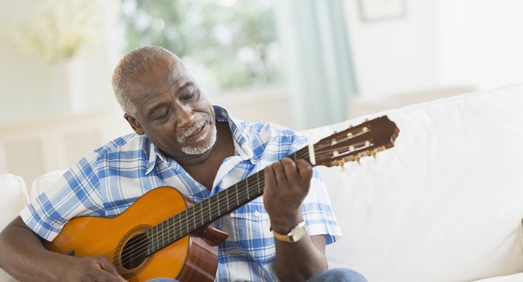 man on couch playing a guitar