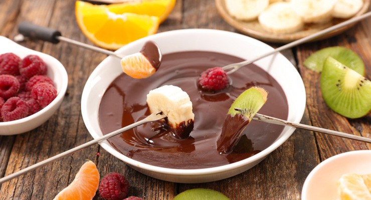 bowl of melted chocolate and fruit on skewers