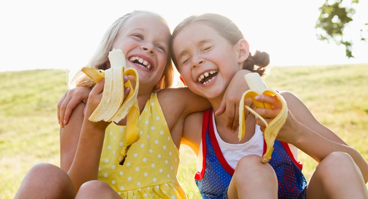 two cute girls eating bananas