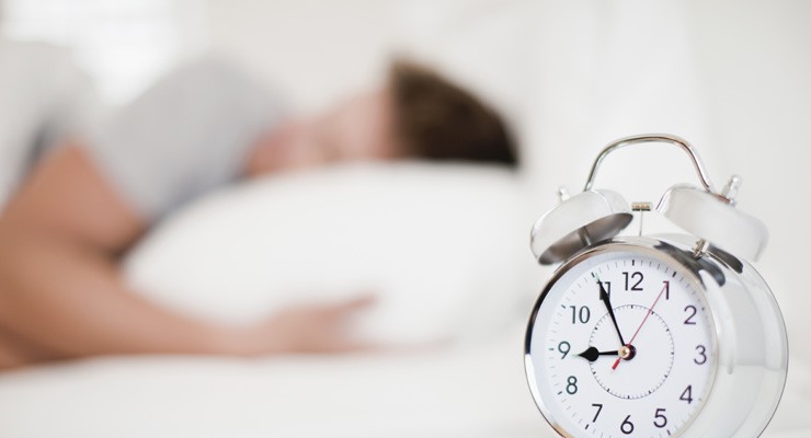 man sleeping with alarm clock in the foreground
