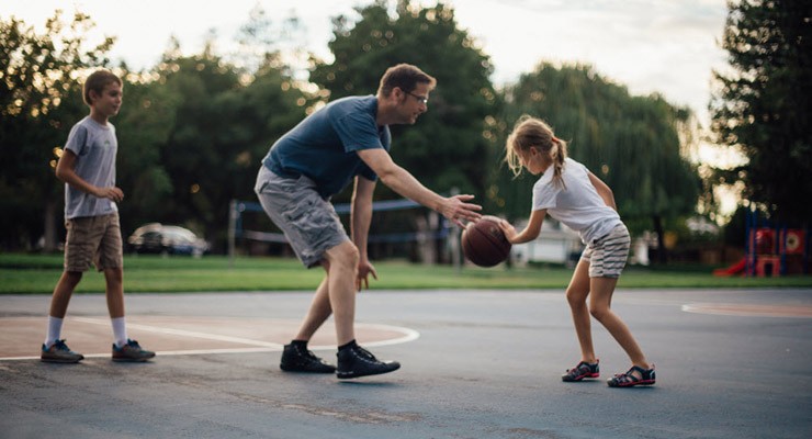 family playing basketball outside.