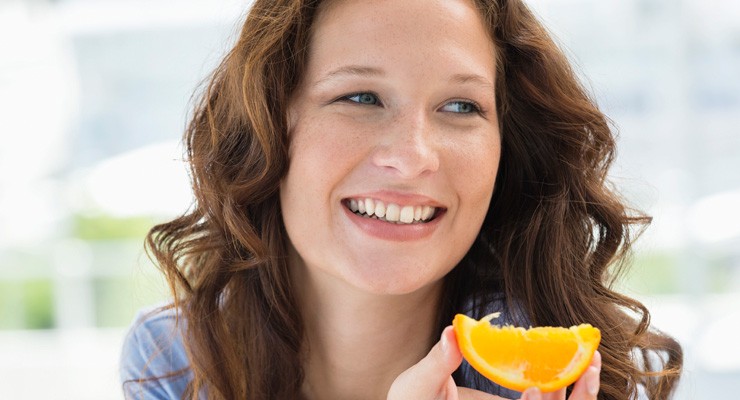 woman eating wedge of orange